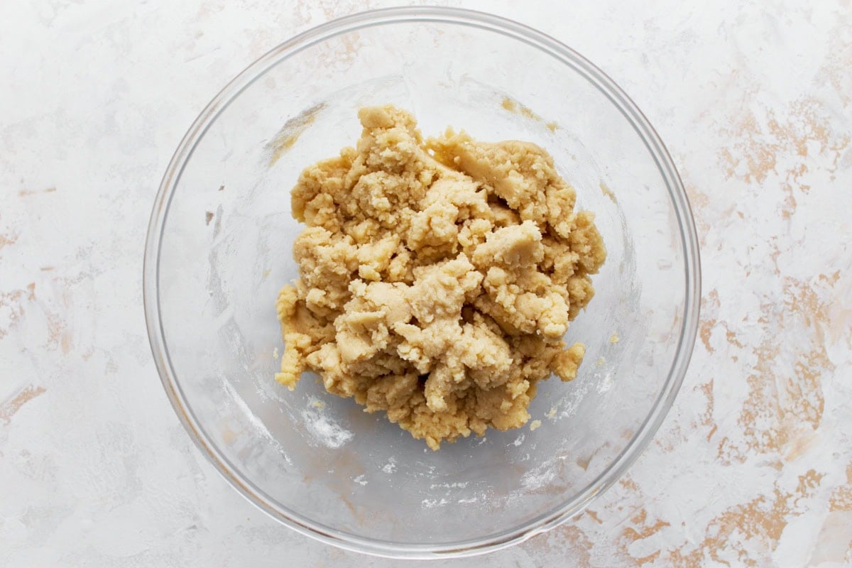Gluten-free shortbread dough and crumbly in a glass mixing bowl.