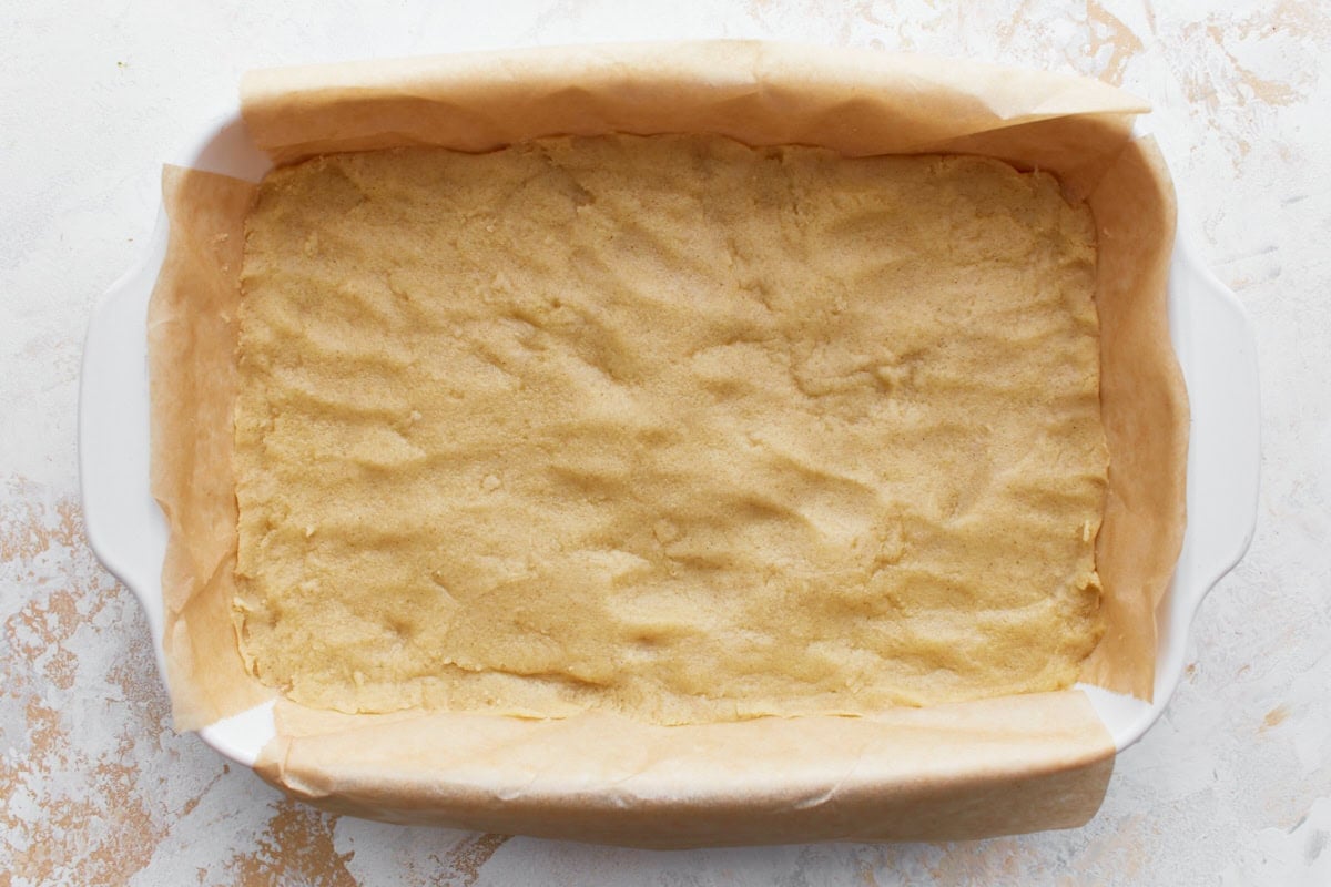 gluten-free shortbread crust pressed into a parchment paper lined baking dish