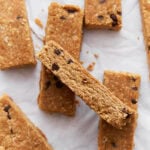 Homemade gluten-free granola bars stacked on parchment paper, showing their golden brown texture and chocolate chip details.
