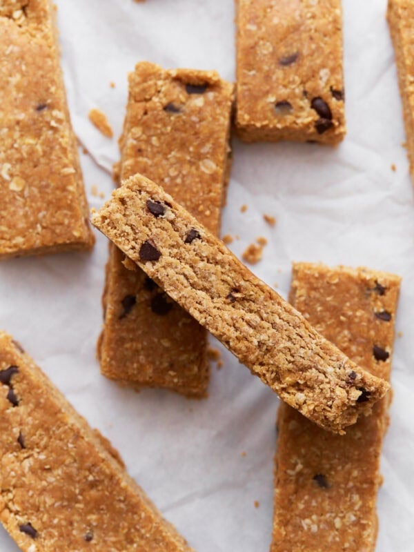 Homemade gluten-free granola bars stacked on parchment paper, showing their golden brown texture and chocolate chip details.
