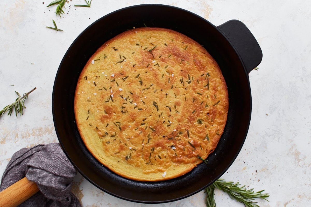 Freshly baked farinata in a skillet, garnished with rosemary and salt.