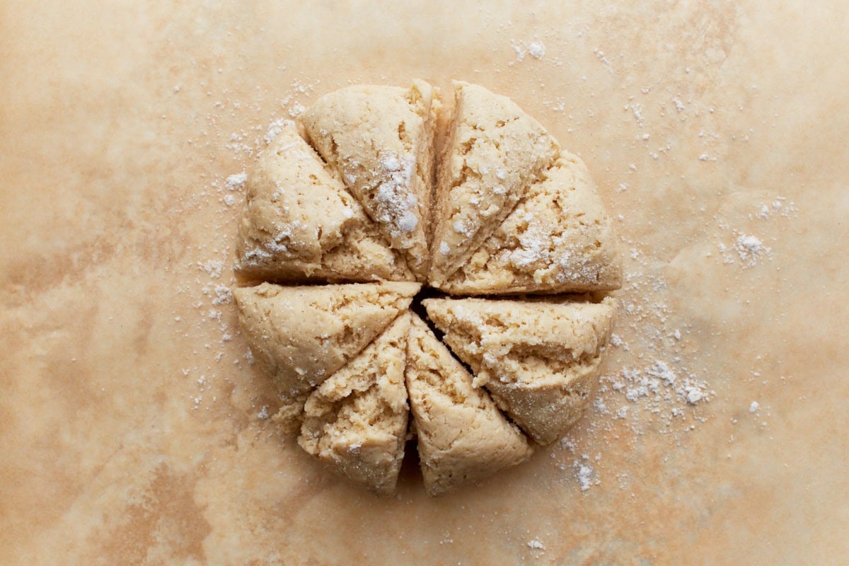 Gluten-free naan dough divided into eight equal portions, dusted with flour, and arranged on a lightly floured surface.