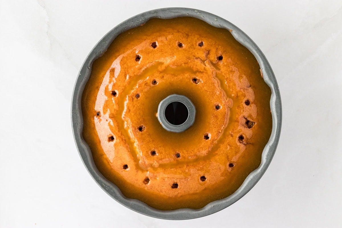 The Gluten-Free Kentucky Butter Pound Cake in the Bundt pan with golden butter glaze poured evenly over the surface, soaking into the cake through the holes.