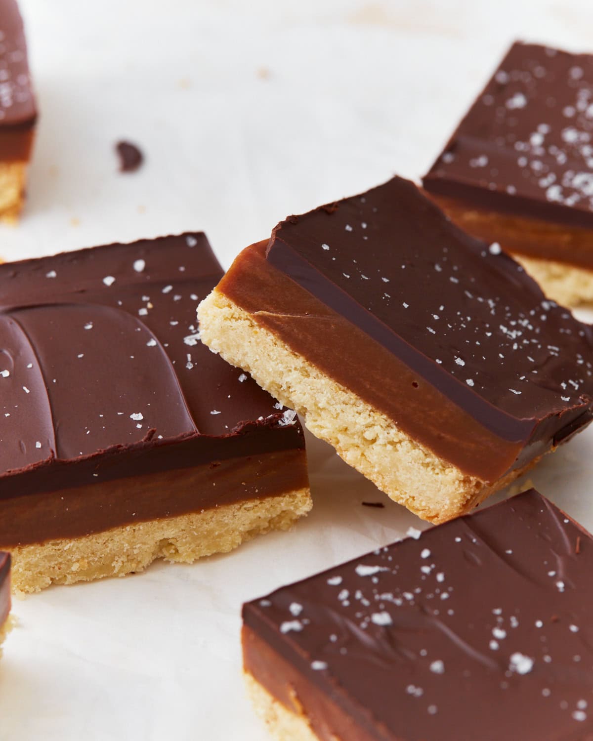 A stack of two gluten-free millionaire shortbread slices showing the distinct layers of chocolate, caramel, and shortbread.