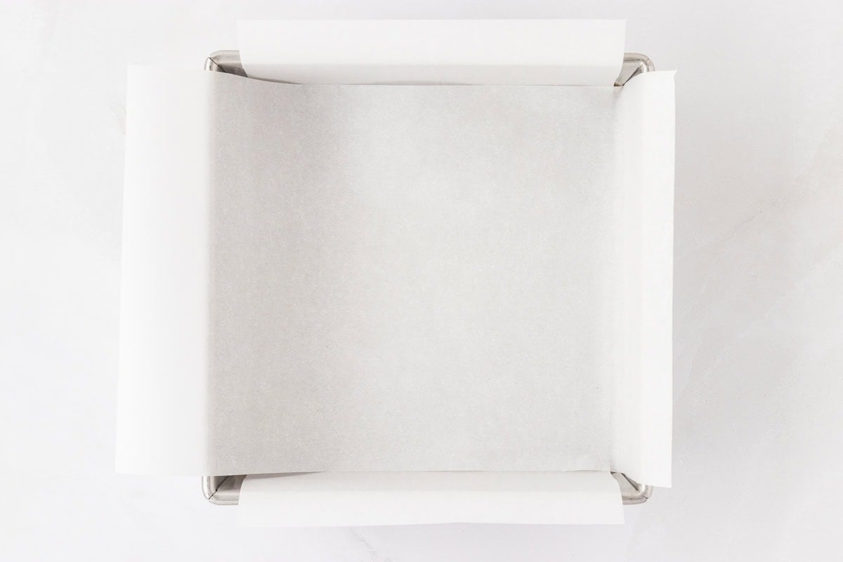 A baking pan lined with parchment paper, prepared and ready for the banana oatmeal bar batter.