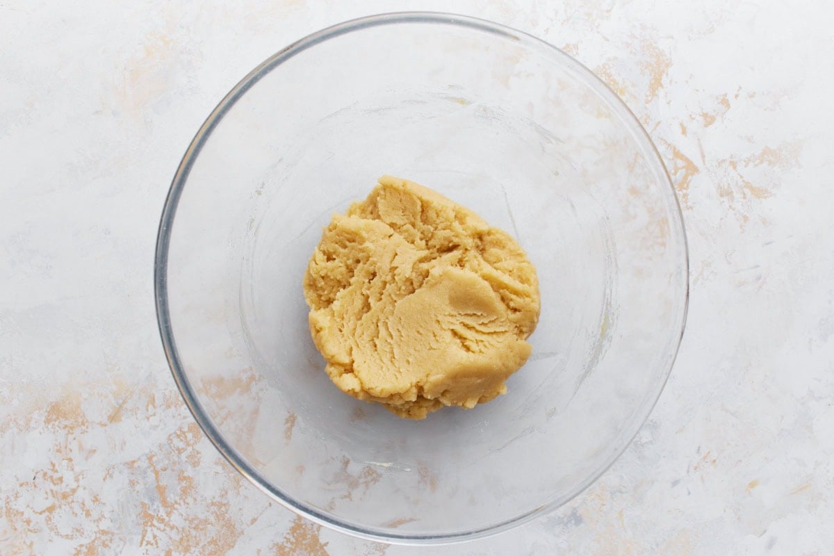 A glass mixing bowl with creamy gluten-free shortbread dough, ready to be pressed into a baking pan.