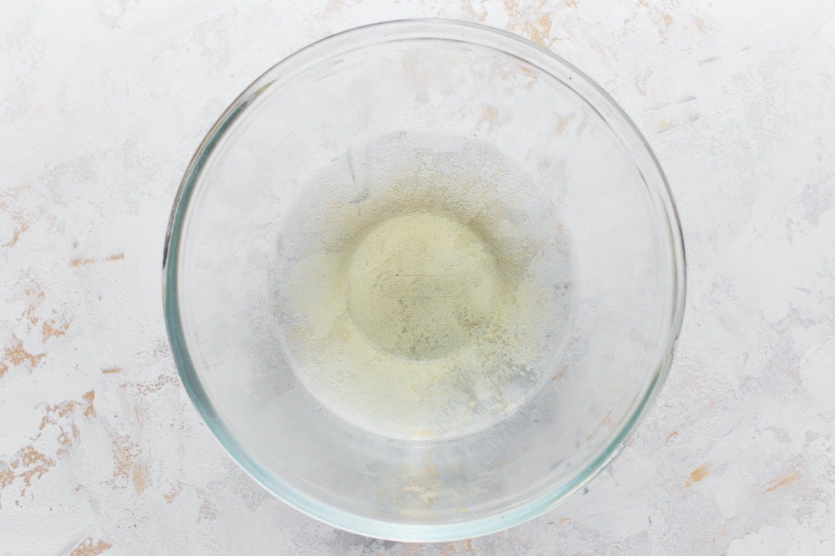 An empty glass mixing bowl lightly dusted with yeast powder.