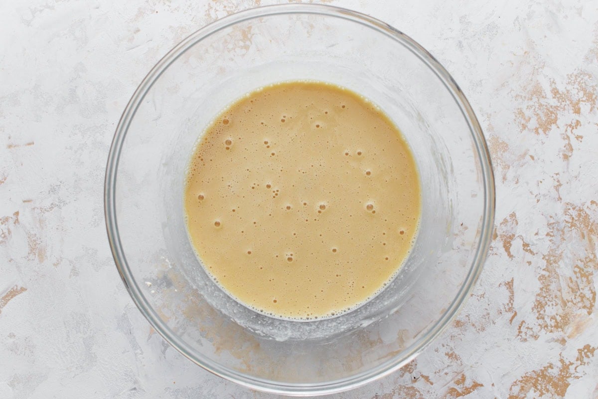 Another view of mixed chickpea batter in a glass bowl.