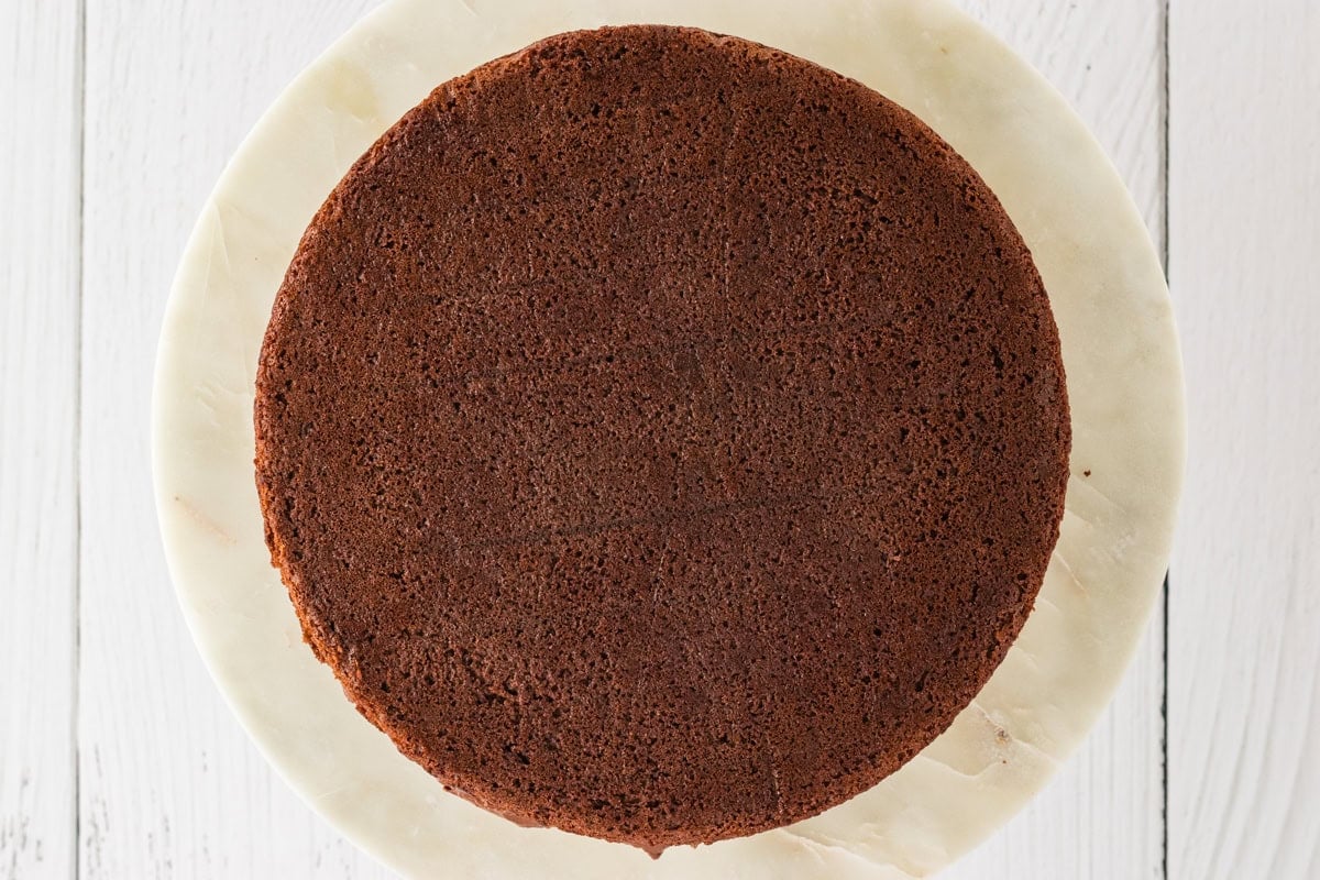 The second gluten-free chocolate cake layer placed on top of the frosted bottom layer, completing the cake assembly.