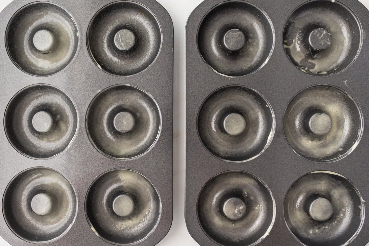 Two greased donut pans ready for filling, coated with nonstick spray to ensure the donuts release easily after baking.