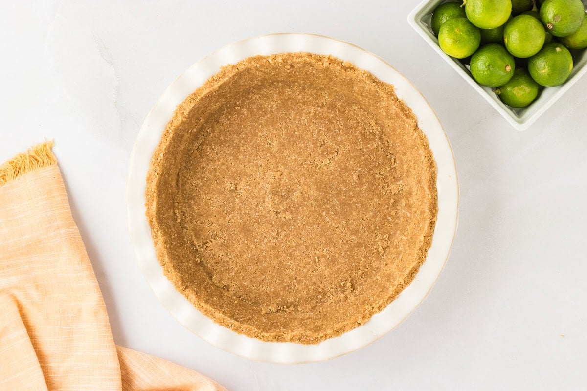 A fully pressed and shaped gluten-free pie crust in a white pie dish, ready for baking.