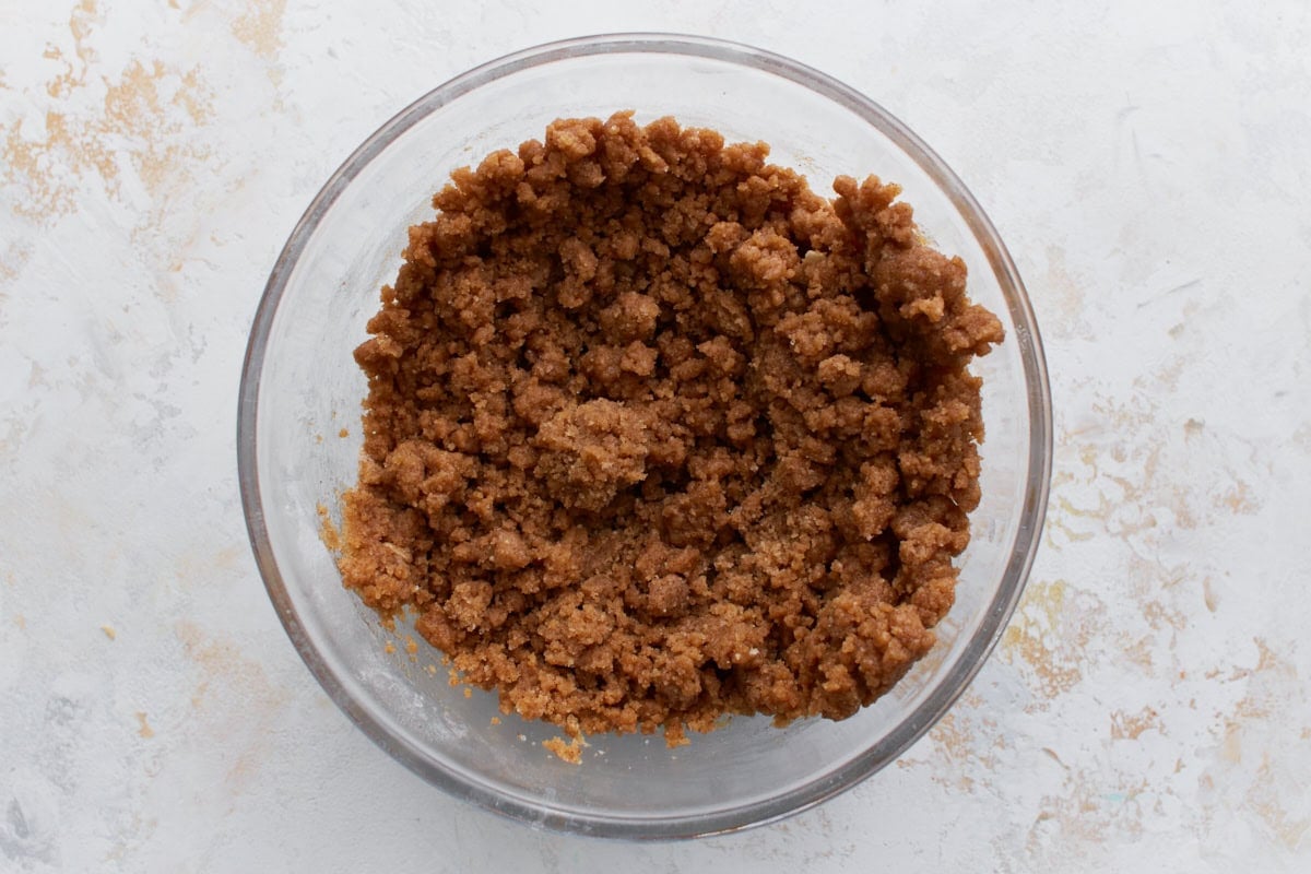 A glass bowl filled with a crumbly cinnamon-sugar streusel mixture, ready to be sprinkled over the cake batter