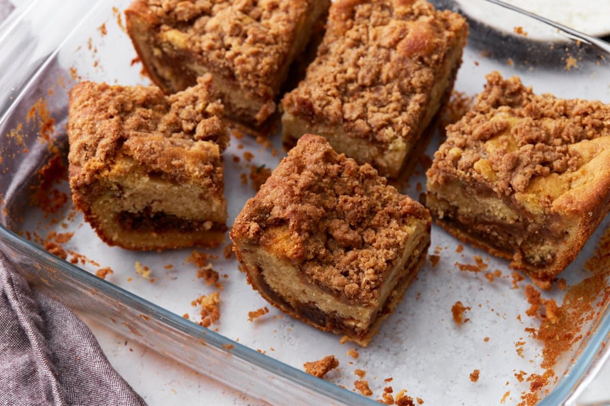 A glass baking dish with the cake cut into square pieces, revealing the layers of soft cake, cinnamon filling, and crunchy streusel topping.