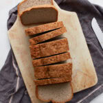 Sliced buckwheat bread resting on a cutting board with one slice removed and placed beside the loaf.