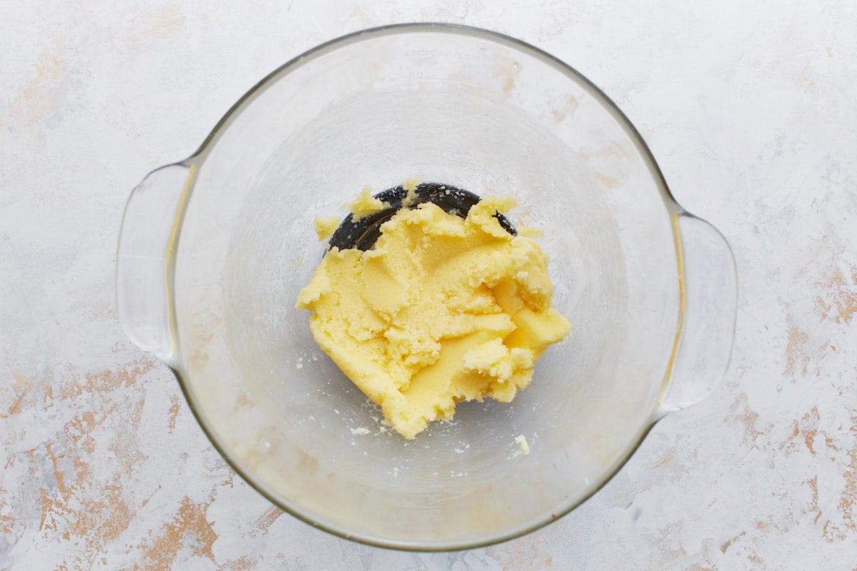 A glass mixing bowl with softened butter and sugar creamed together until fluffy.