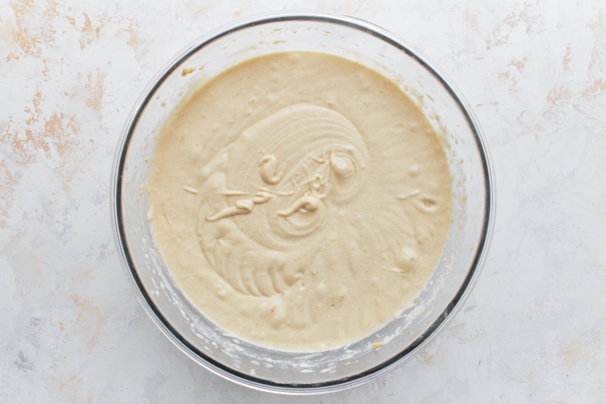 A large mixing bowl filled with fully mixed gluten-free cake batter, showing a smooth and creamy consistency.