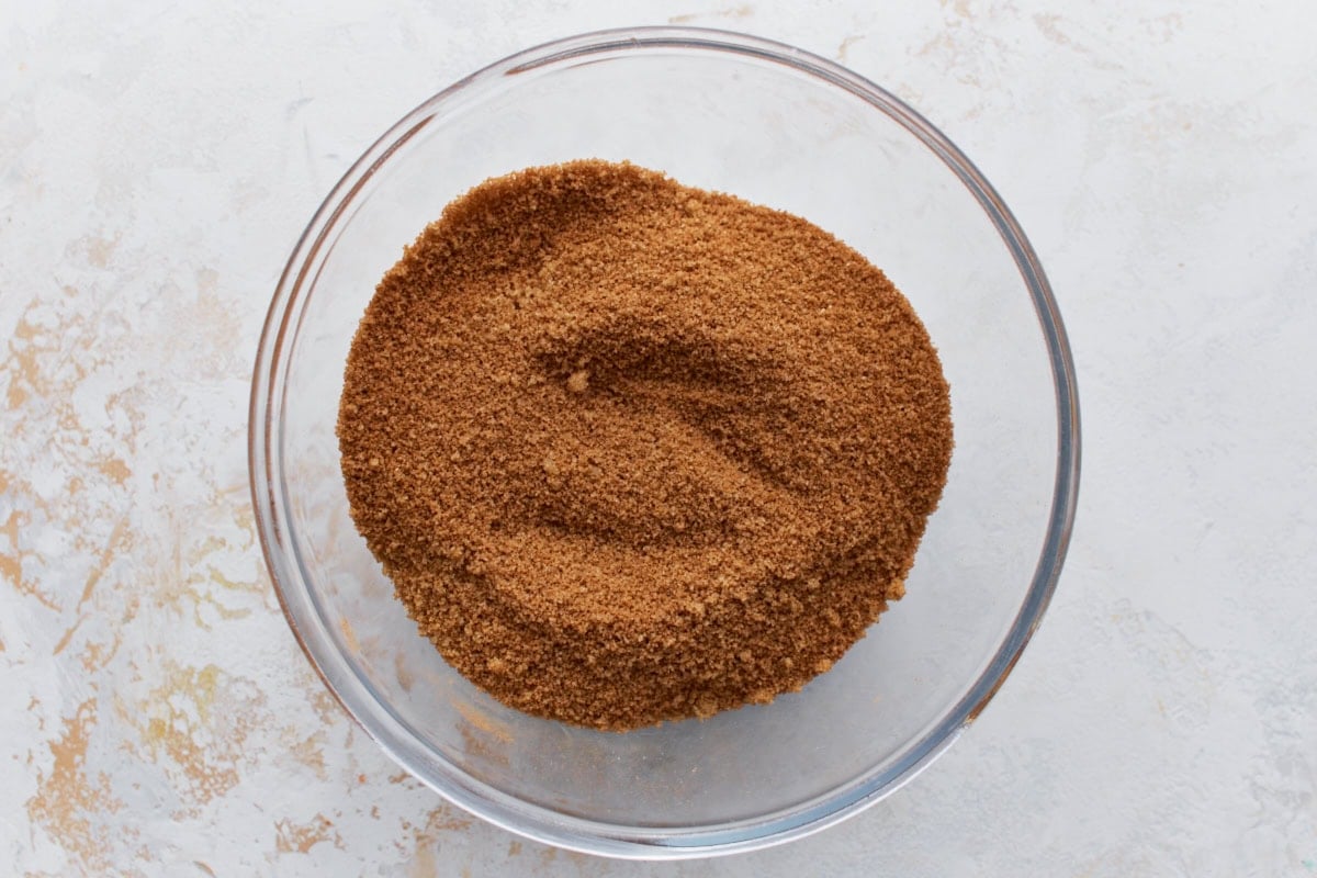 A glass bowl filled with a mixture of brown sugar and cinnamon, evenly blended and ready to be layered into the cake.