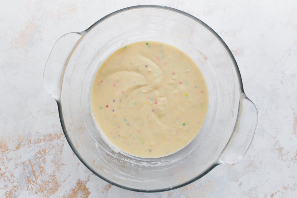 A bowl of gluten-free cake batter with colorful sprinkles evenly mixed in.