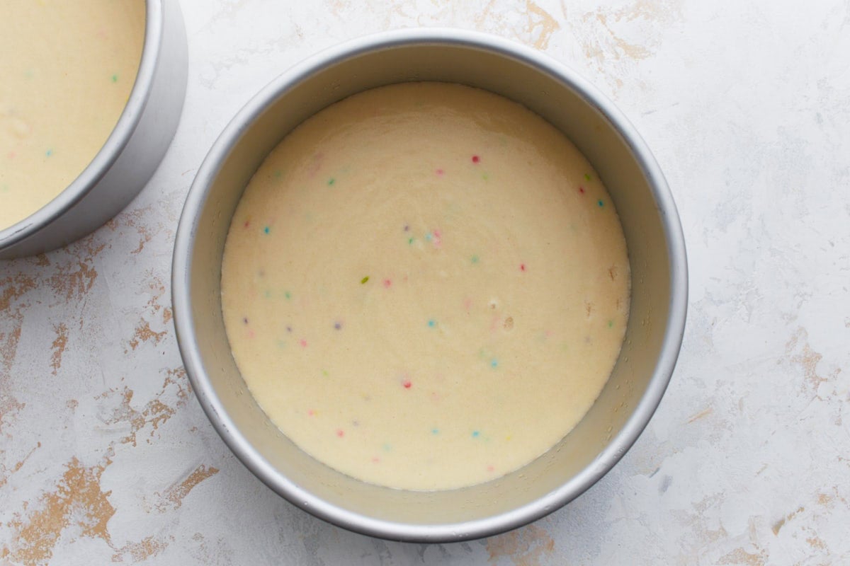 Two round cake pans filled with funfetti cake batter, ready to be baked.