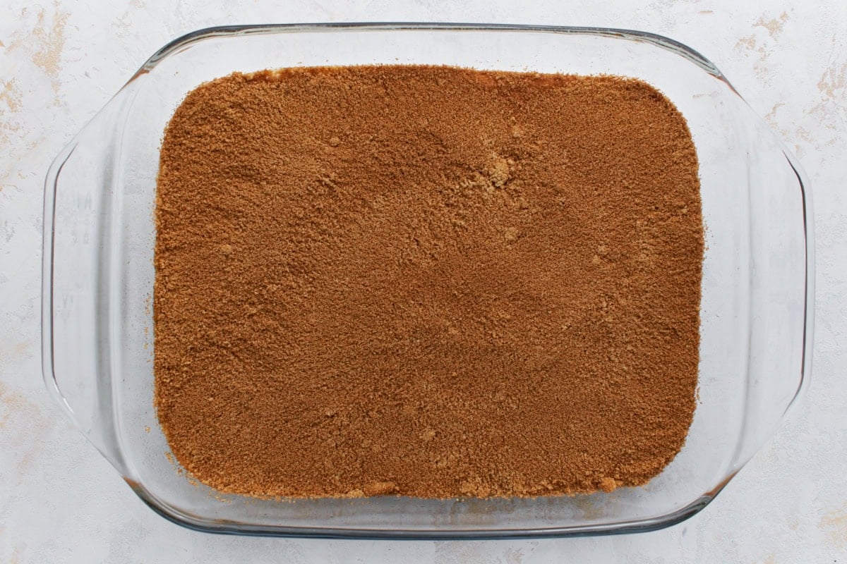A glass baking dish with an even layer of cinnamon sugar filling covering the first layer of cake batter.