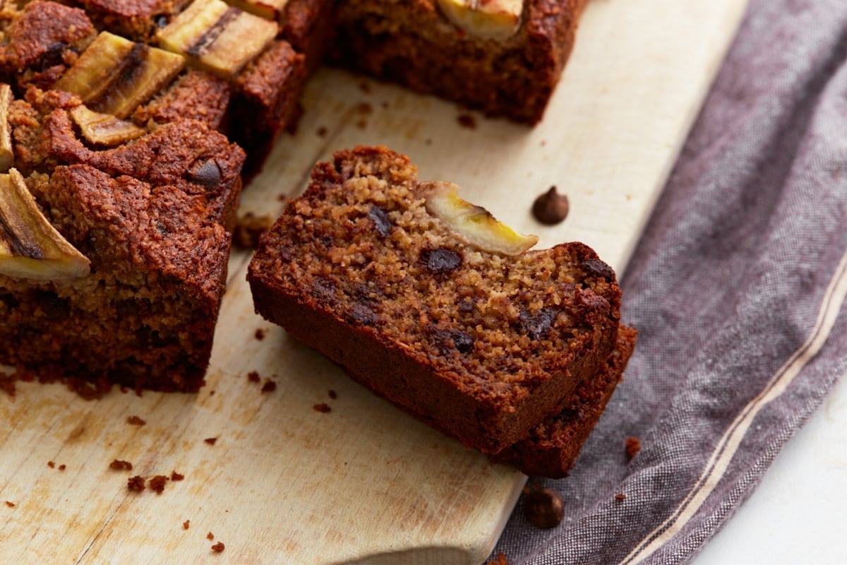 A close-up of a single slice of banana oatmeal bread showing its moist interior, melty chocolate chips, and a piece of baked banana on top.