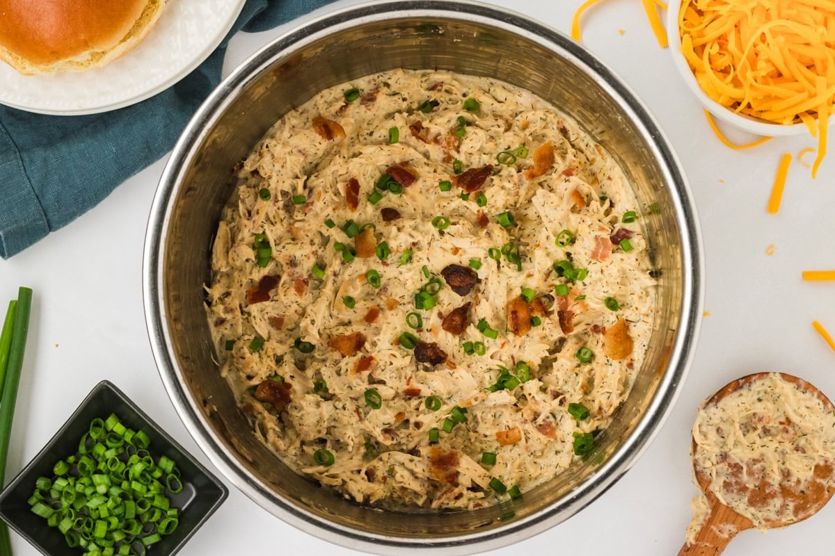 Final crack chicken mixture in the Instant Pot, fully stirred together and garnished with bacon and green onions.