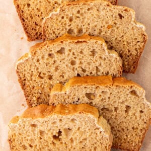 Overhead view of several slices of cassava bread arranged on parchment paper, showing a golden crust and airy crumb.