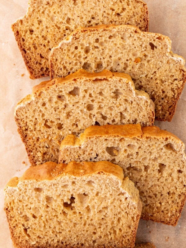 Overhead view of several slices of cassava bread arranged on parchment paper, showing a golden crust and airy crumb.