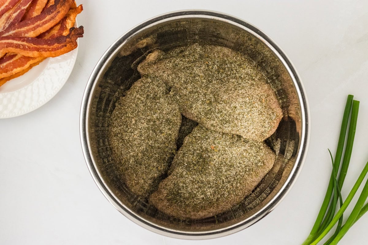 Chicken breasts coated in a generous layer of dry ranch seasoning mix inside the Instant Pot insert.