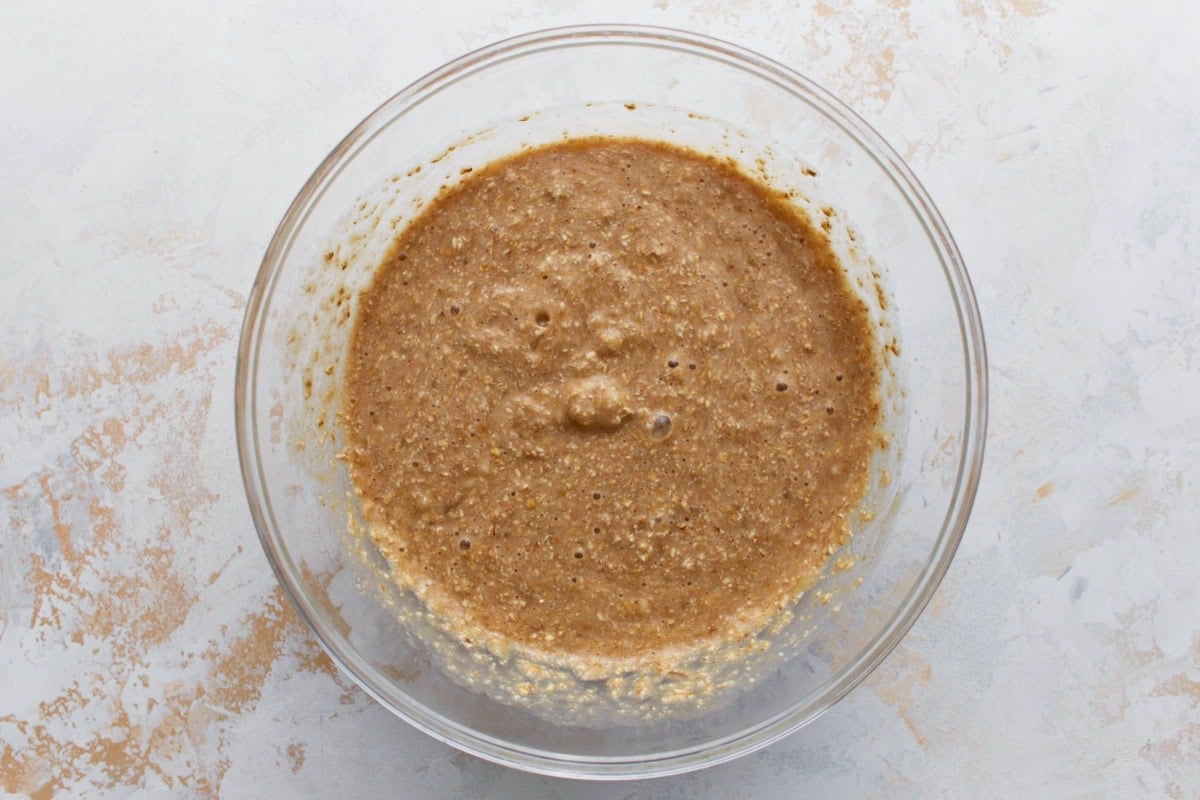A mixing bowl filled with wet banana bread batter, showing its thick, bubbly texture.