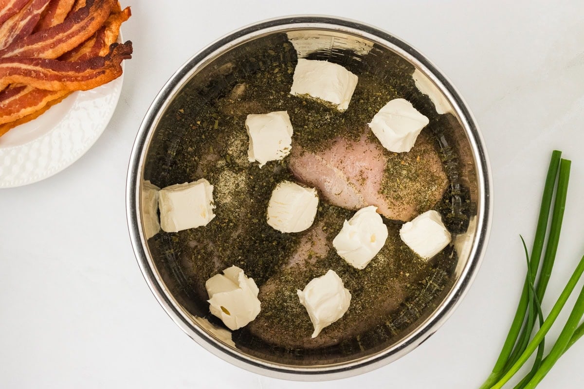 Cubes of cream cheese added on top of the seasoned chicken breasts inside the Instant Pot.