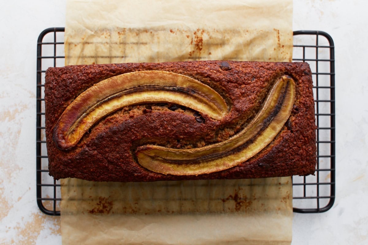 Freshly baked banana oatmeal bread cooling on a wire rack, featuring golden brown edges and caramelized banana slices on top.