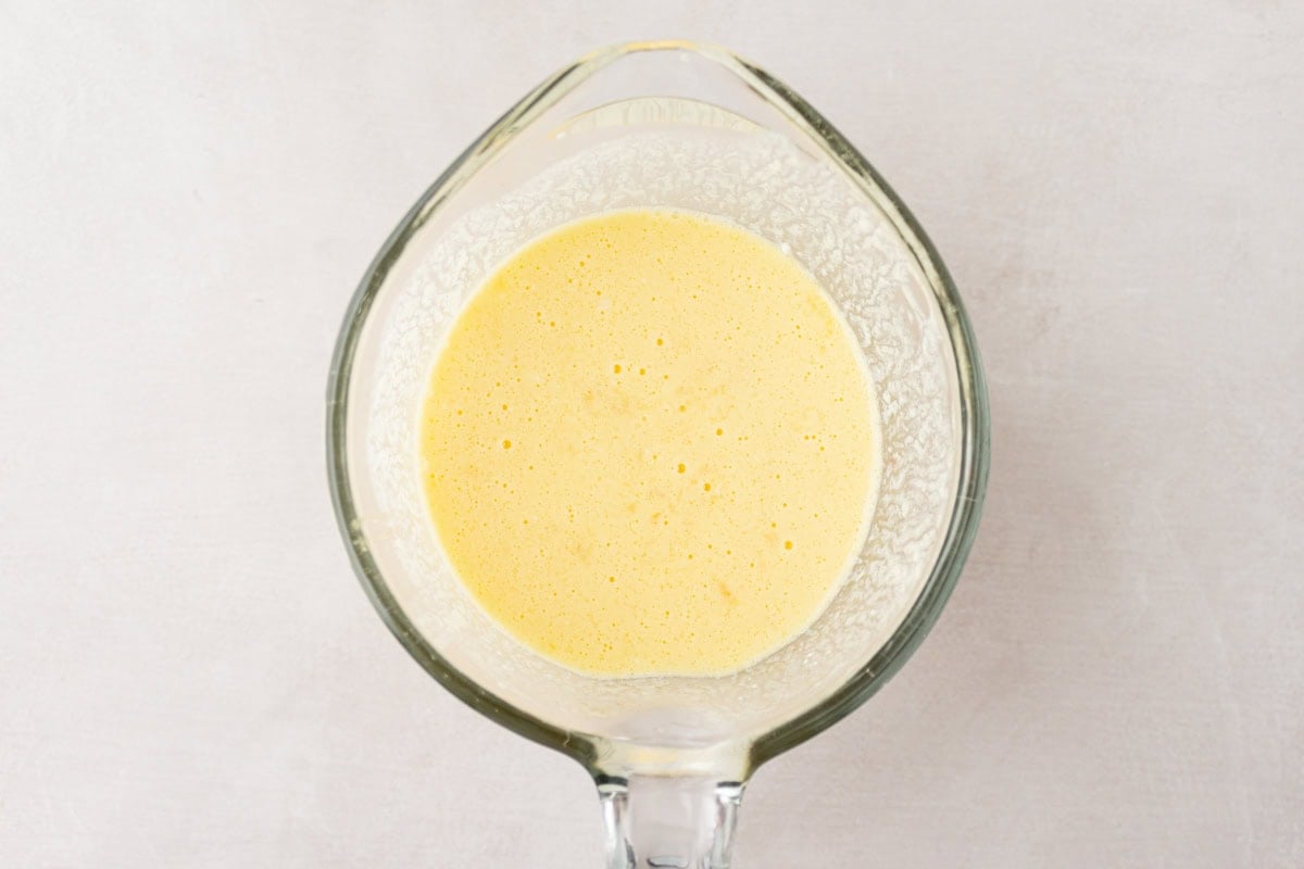 Top-down view of a glass measuring cup filled with the blended wet ingredients for cassava bread.