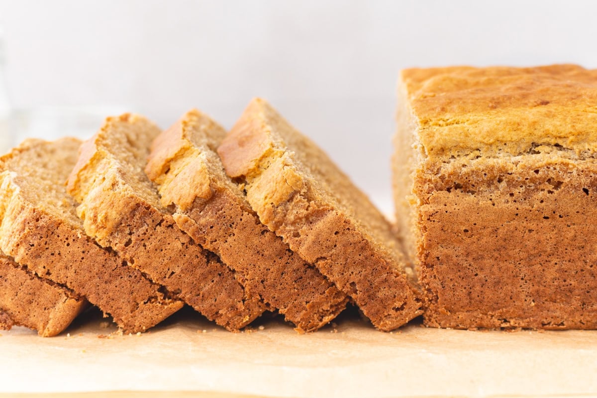Sliced loaf of cassava bread resting on parchment paper, showing a crisp crust and soft interior.