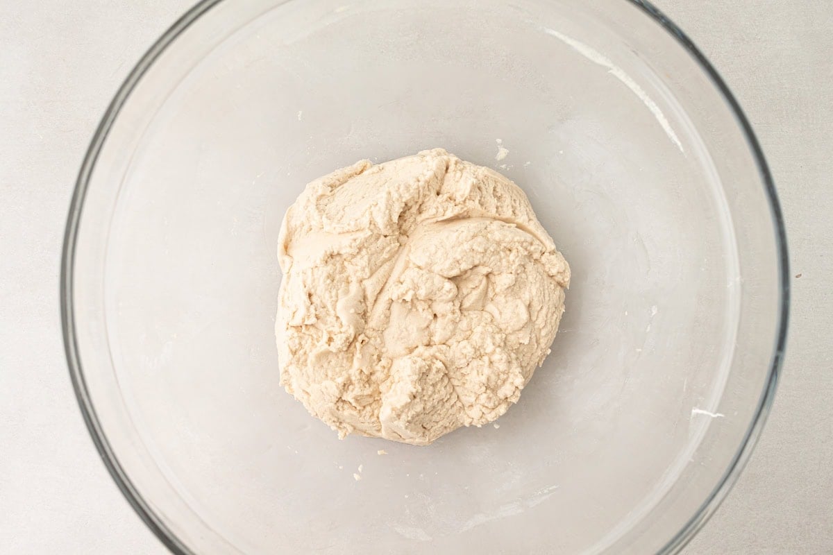 Cassava tortilla dough formed into a cohesive ball inside a glass mixing bowl.