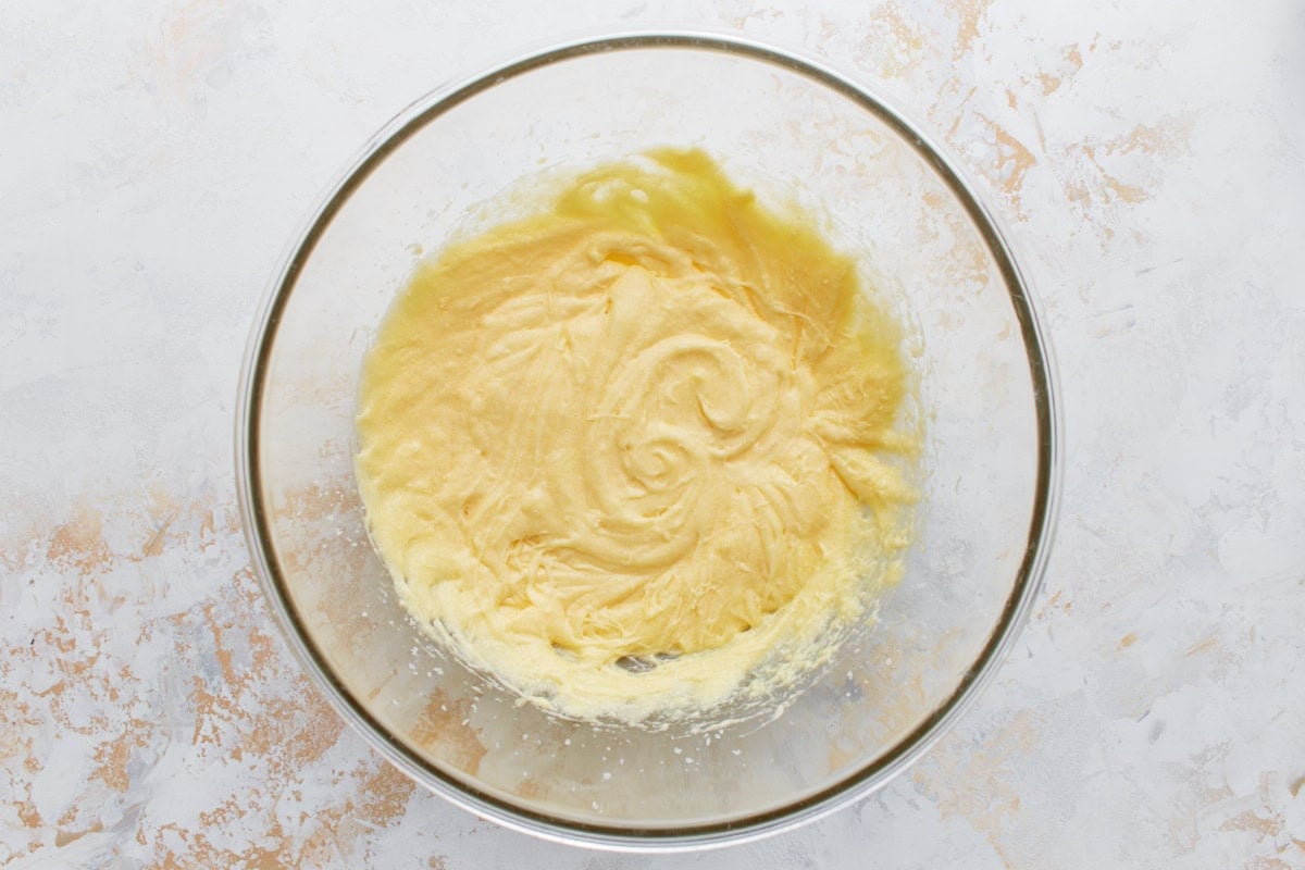 Glass bowl with smooth, pale yellow wet muffin batter swirled in the center.