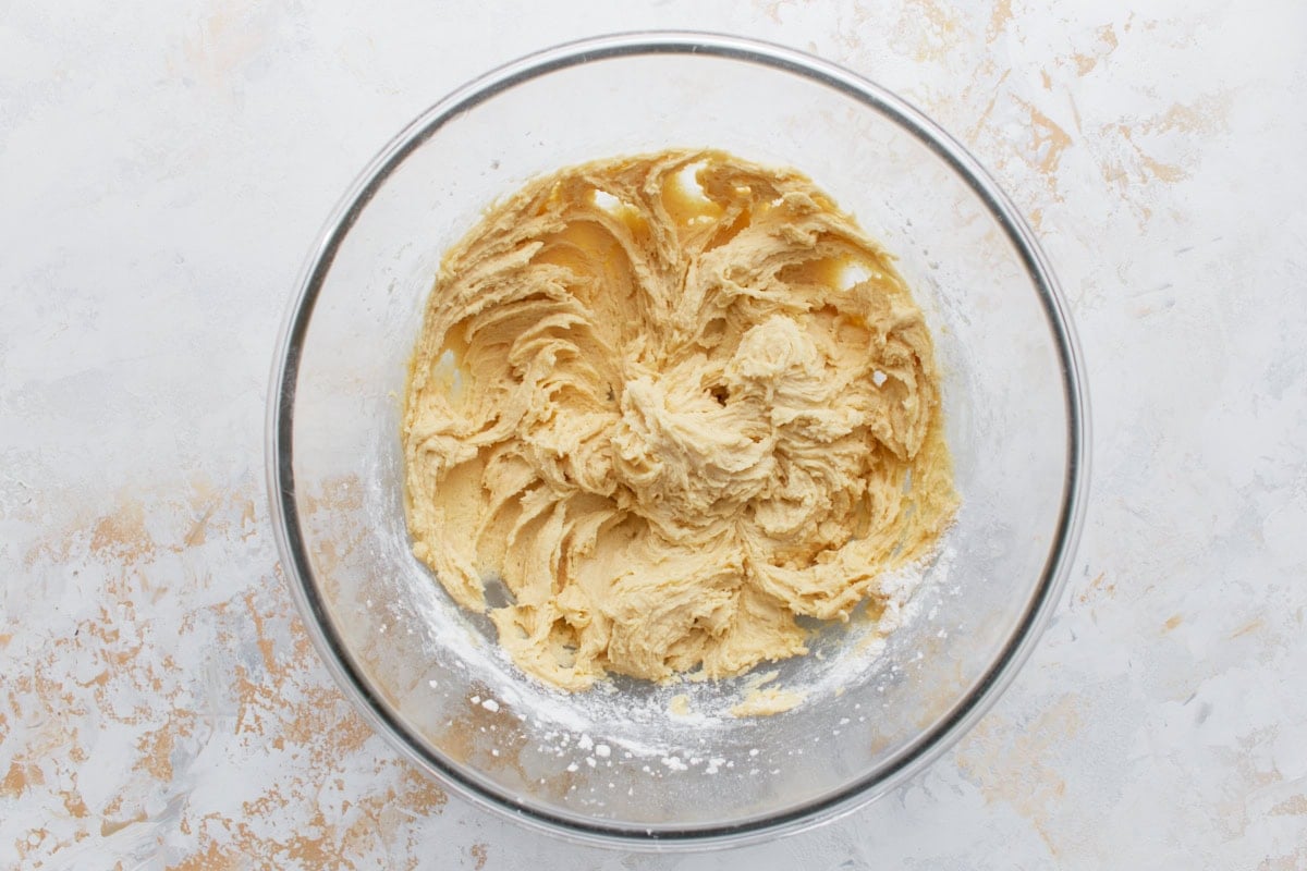 Thick gluten-free muffin batter in a glass bowl after dry ingredients have been added, before blueberries are folded in.