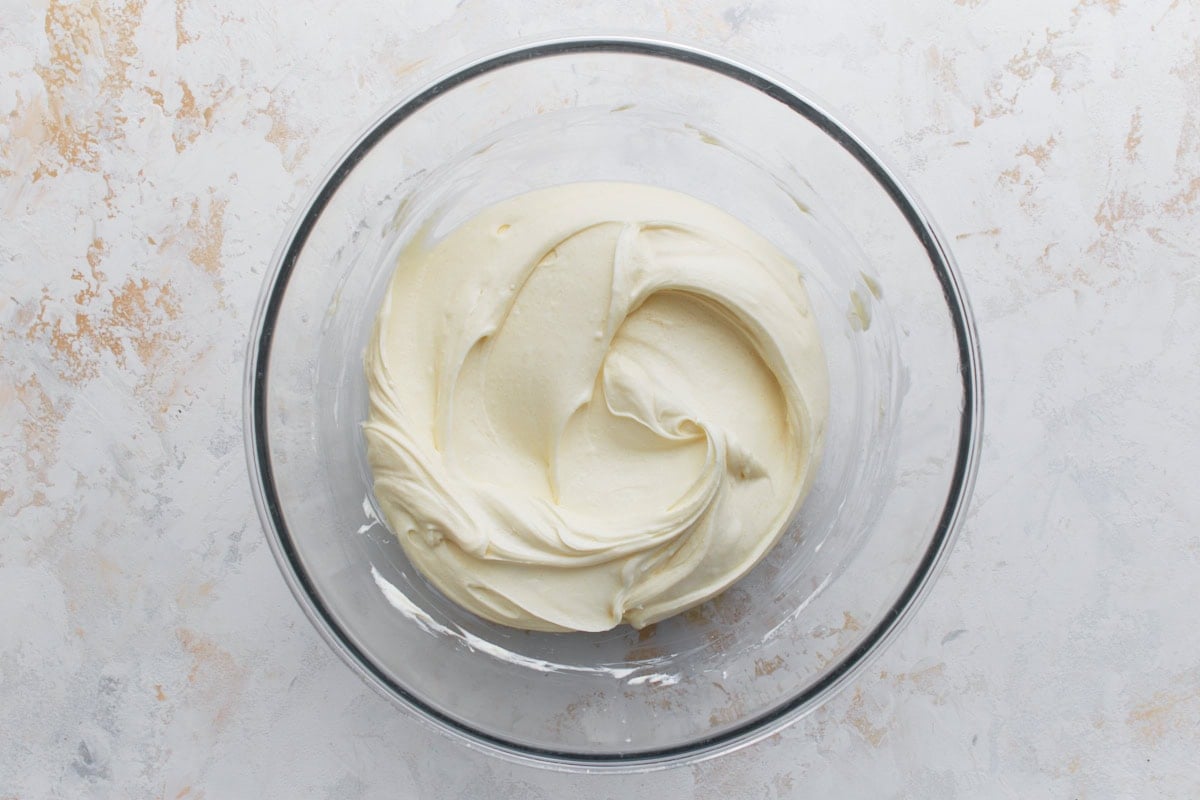 Bowl of whipped cream cheese mixture showing the creamy and smooth cheesecake filling.