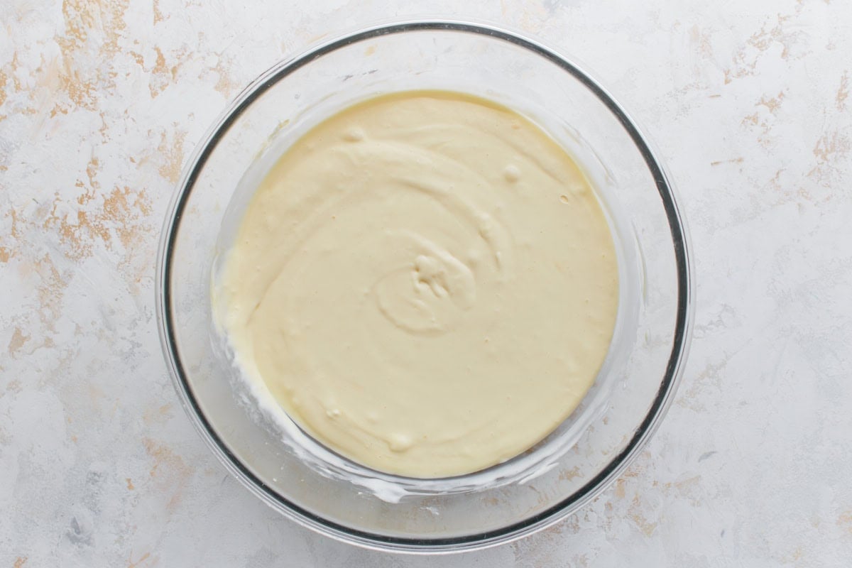 Bowl of cheesecake batter after adding sour cream, eggs, and cornstarch, ready to pour into the crust.