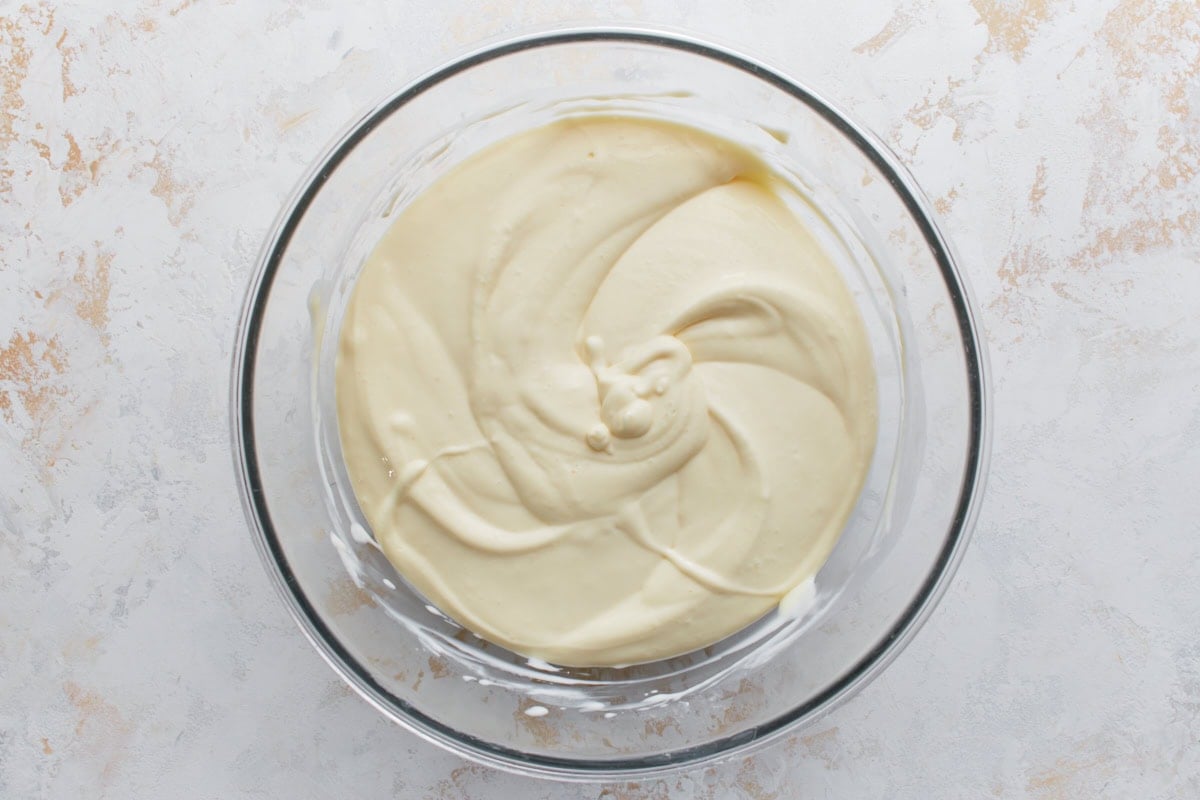 Another view of cheesecake batter mixed and swirled to a smooth consistency in a glass bowl.