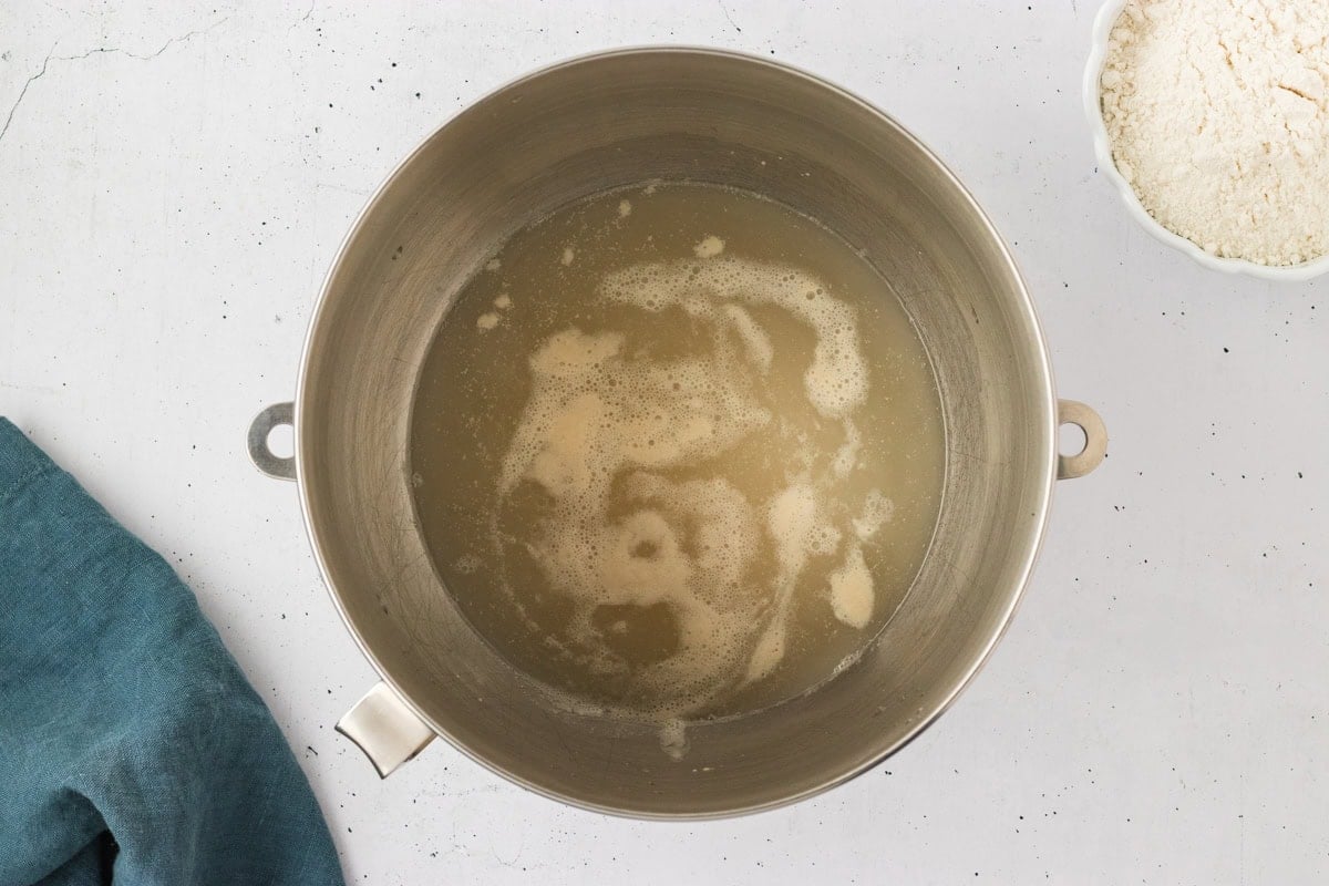 Activated yeast mixture in a mixing bowl, showing bubbles and foam on the surface after sitting for 5 minutes.
