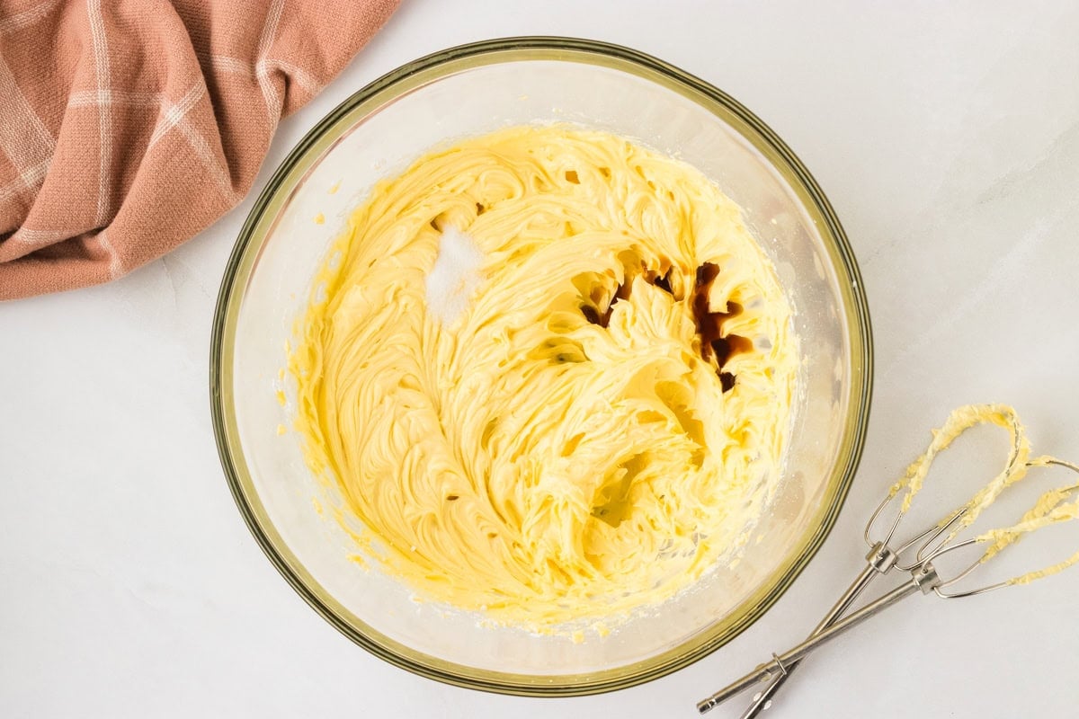 Vanilla extract and salt added to the butter and sugar mixture in the bowl.