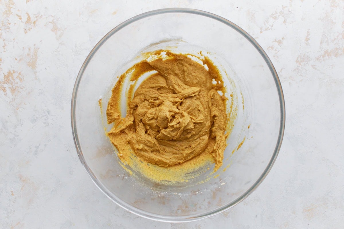 Thick golden pakora batter in a glass bowl, made from chickpea flour, water, and spices.