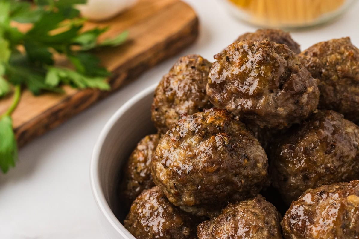 Glossy, golden-brown gluten-free meatballs stacked in a white bowl, ready to serve.