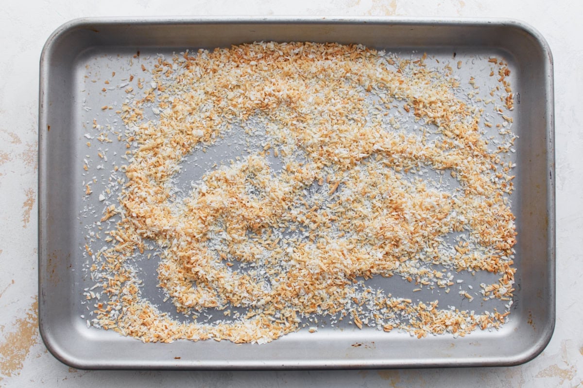 Toasted shredded coconut spread on a baking sheet, golden and crisp.