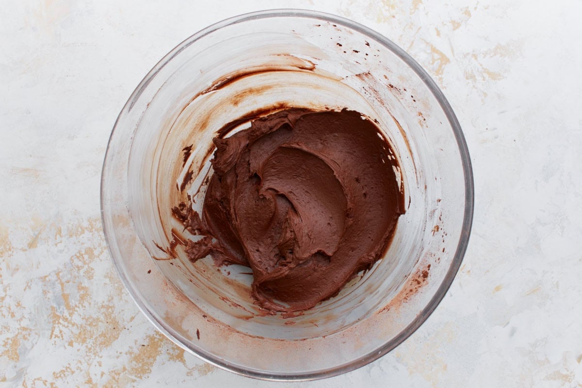 Rich chocolate frosting beginning to come together, with dark cocoa swirled into the butter mixture.