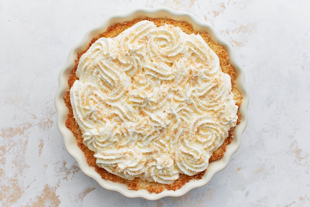 Coconut cream pie fully assembled with toasted coconut sprinkled over whipped topping.
