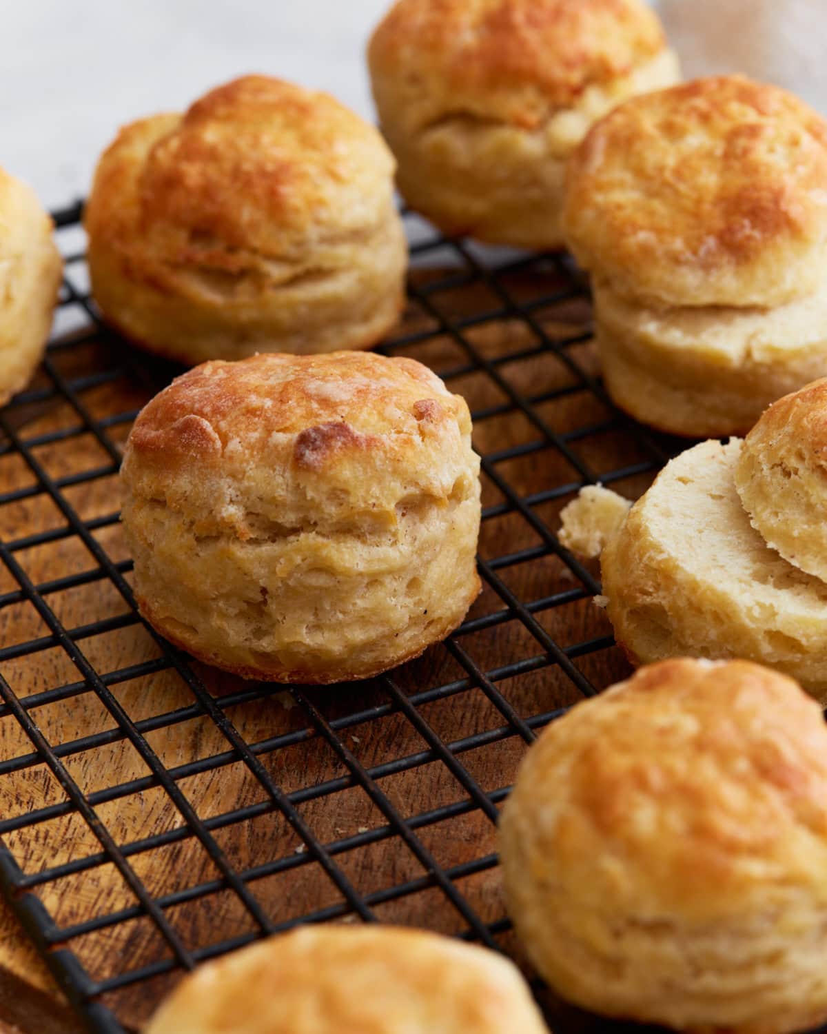 Freshly baked gluten-free buttermilk biscuits cooling on a wire rack, showing golden tops and flaky layers.