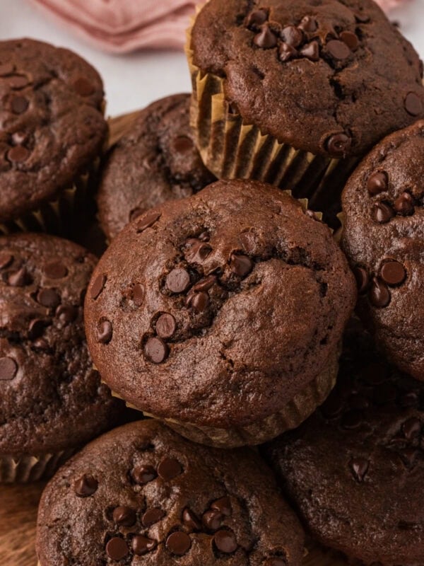 Close-up of a stack of gluten-free double chocolate muffins topped with melty chocolate chips.