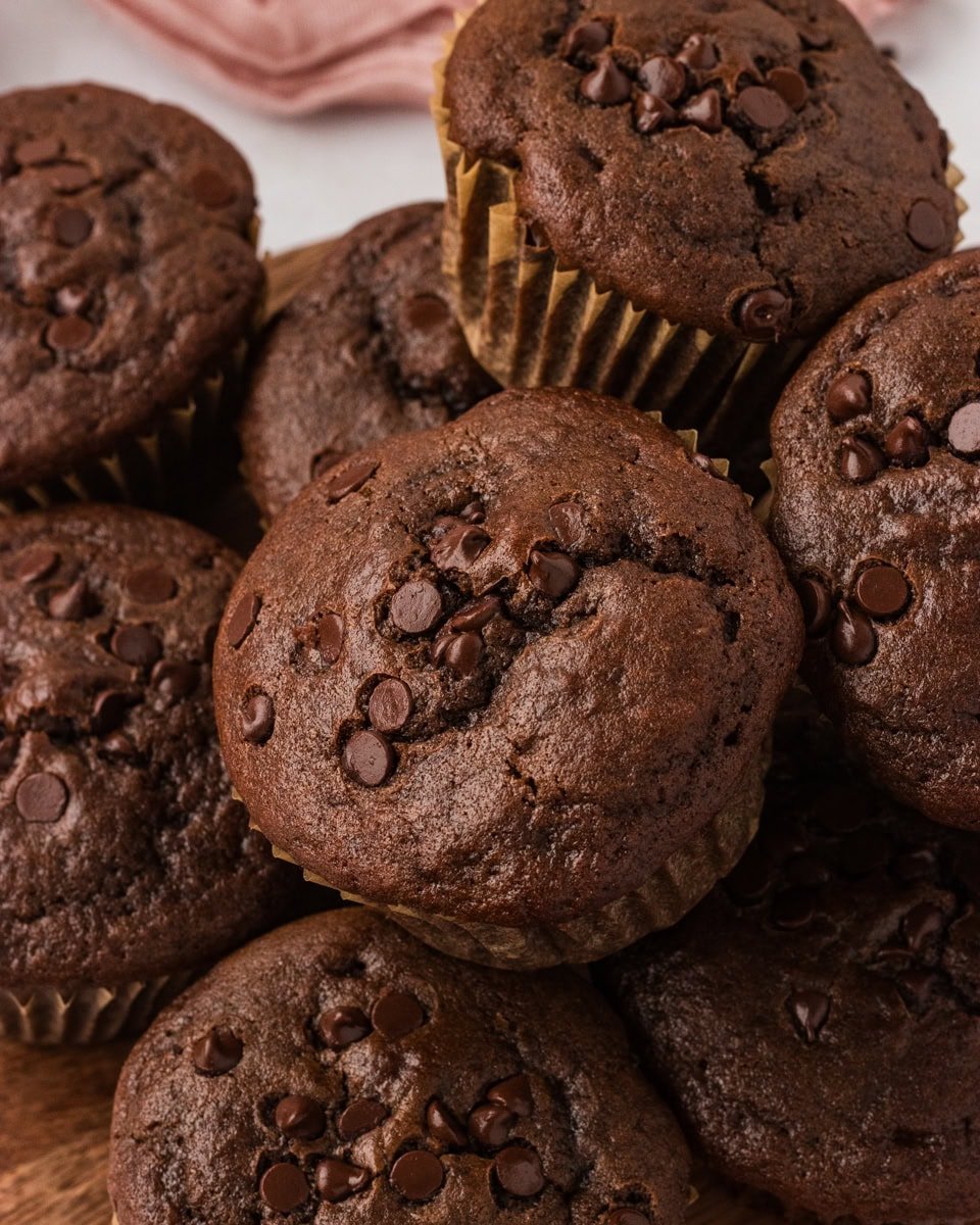 Close-up of a stack of gluten-free double chocolate muffins topped with melty chocolate chips.